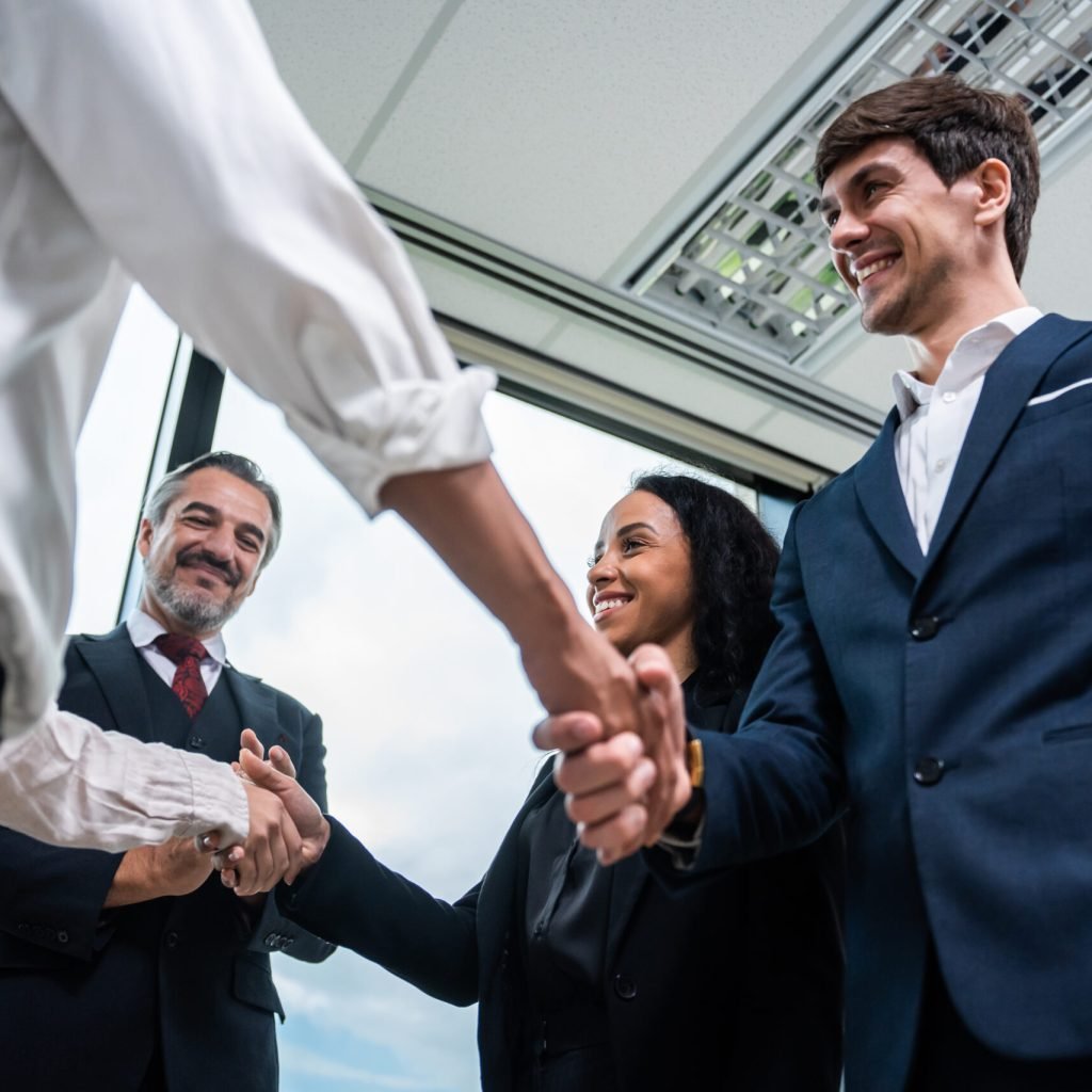 Caucasian businessman making a handshake together while stand in office. Attractive team of employee worker enjoy partnership agreement after negotiations for business deal during working in corporate