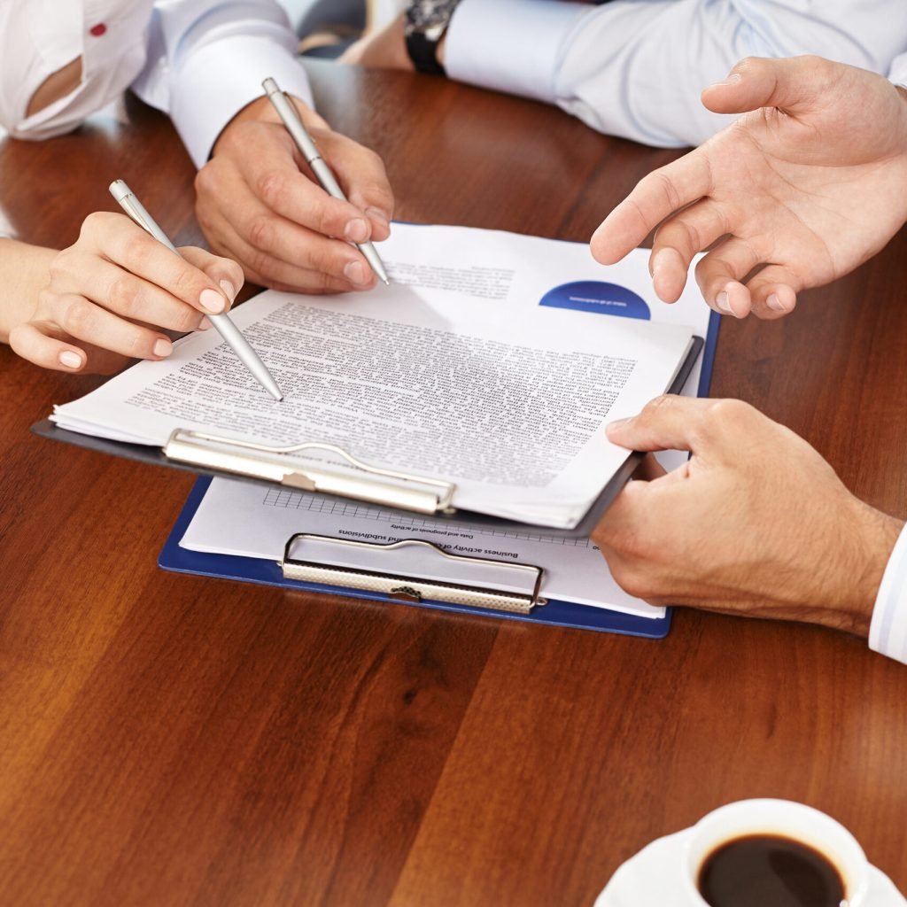 Group of businesspeople pointing at text on paper during discussion